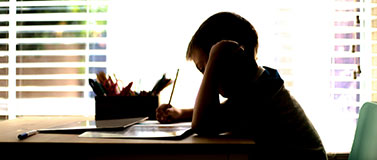 young person sitting at a desk writing with a pencil